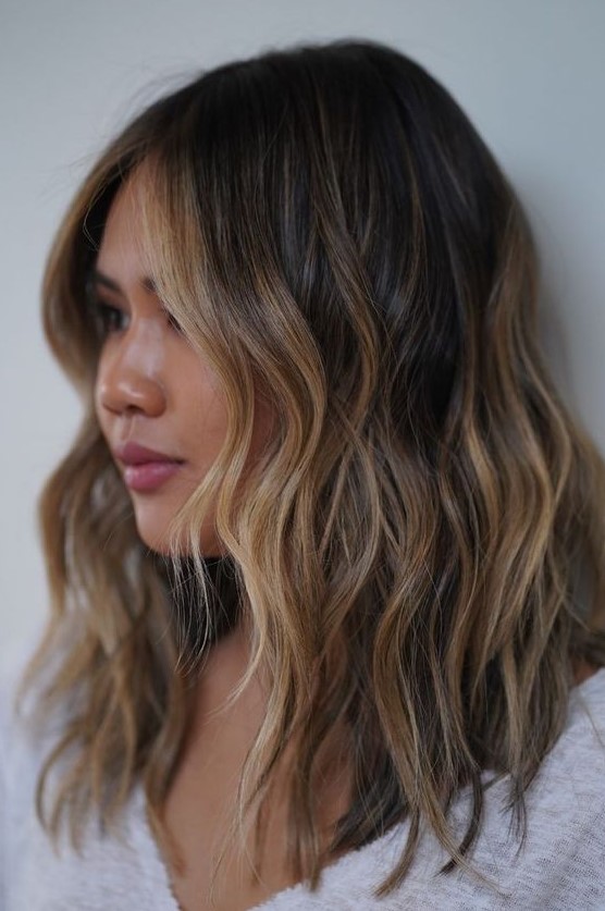 medium-length dark brunette hair with golden blonde highlights and waves is a super chic and catchy idea