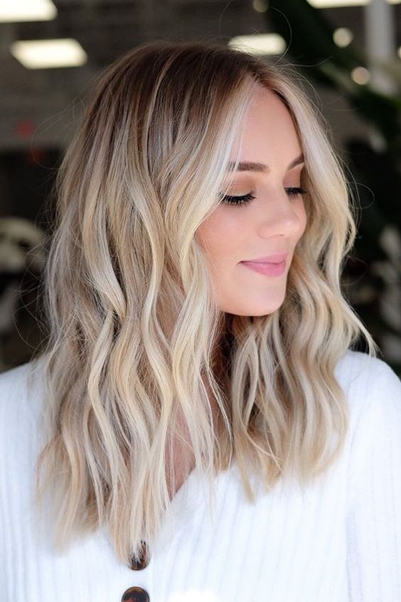 Medium length hair with blonde balayage and waves, a darker root is a chic and cool idea to try right now