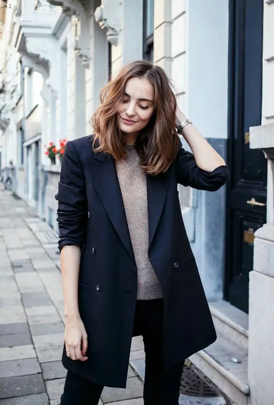 a black double breasted long blazer, a neutral crocheted top and black skinnies