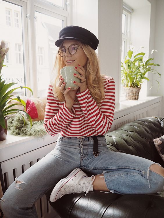 blue distressed jeans, white sneakers, a red and white striped top and a cap