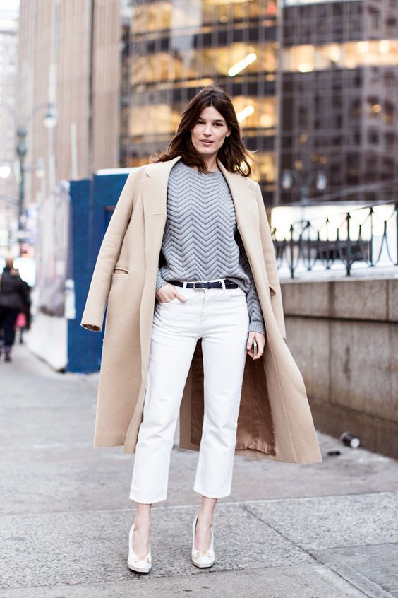 white cropped pants, a grey sweatshirt, white heels and a tan coat