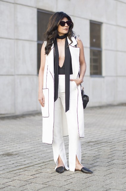 With black top, white long vest, black flat sandals and bag