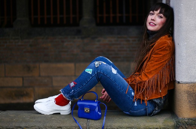 With funny jeans, white sneakers, red socks and blue bag