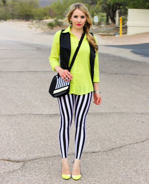 With neon green shirt, black vest, yellow shoes and printed bag