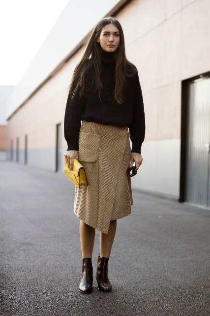 With oversized turtleneck, yellow clutch and ankle boots