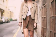 With top, beige jacket, clutch and brown high boots