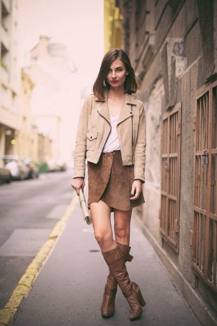 With top, beige jacket, clutch and brown high boots