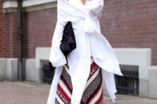 With unique white shirt, red sandals and black clutch