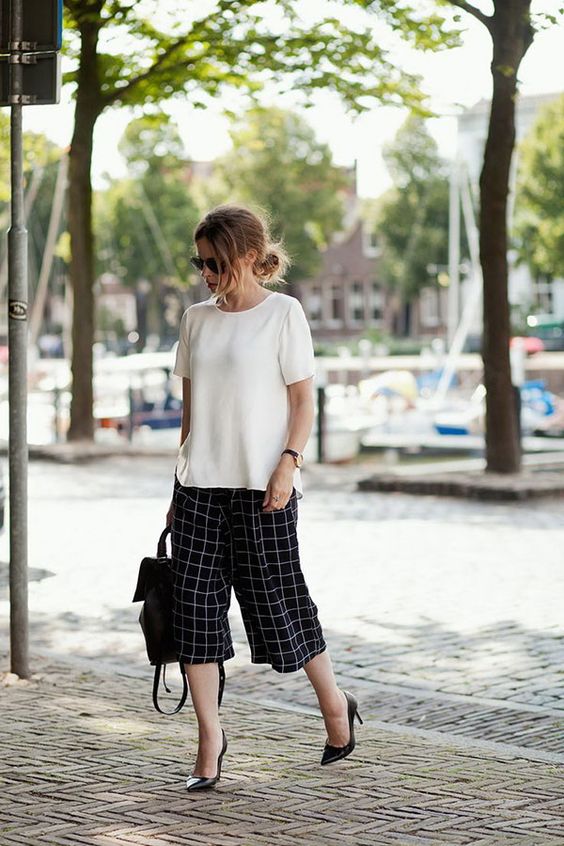 checked black and white culottes, a white top, black heels and a backpack to work