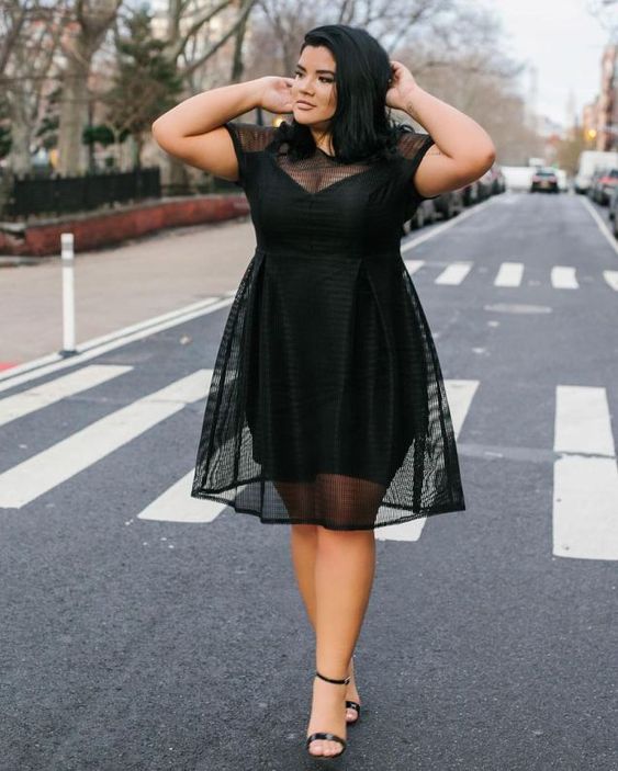 a black knee dress with a sheer overdress, an illusion neckline and trim, black heels