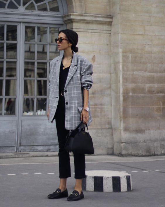 a black top, black cropped pants, an oversized checked blazer and a black bag
