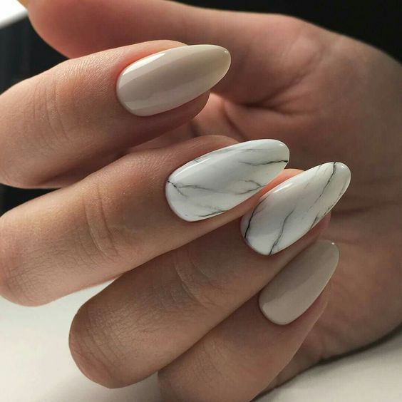 nude nailts plus two accent white marble ones for a trendy look