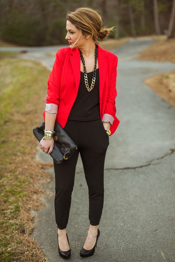 a black jumpsuit, black heels and a clutch, a statement chain necklace and a red blazer