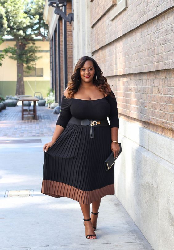 a black off the shoulder midi dress with a color block effect and a pleated skirt, a clutch and heels