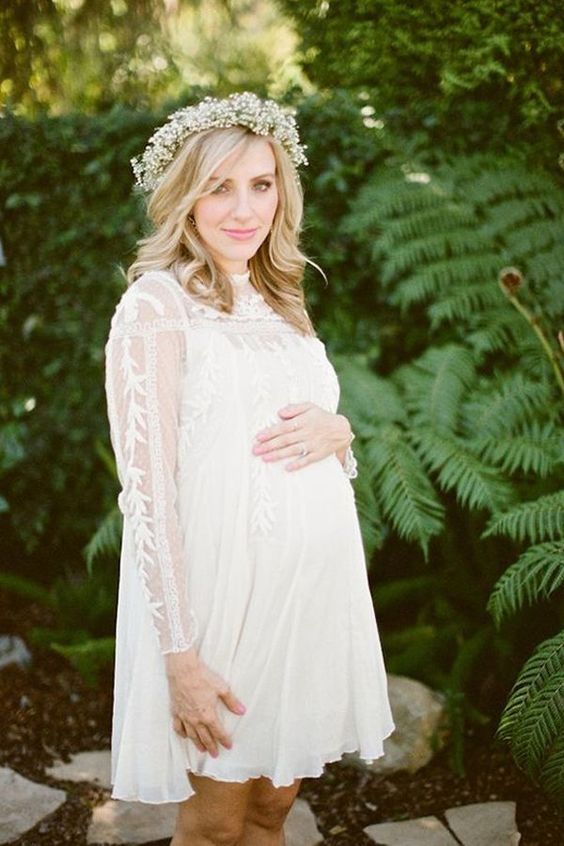 a white lacey over the knee dress with long sleeves and a baby's breath crown