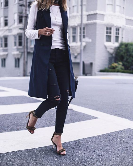 ripped black skinnies, a white long sleeve, a navy long vest and heeled sandals