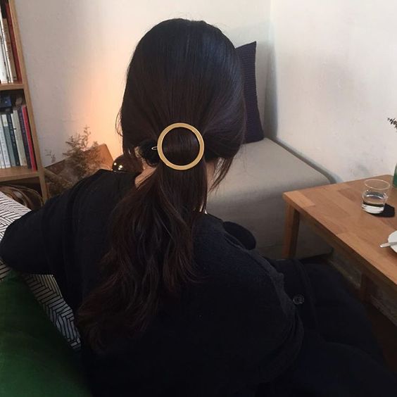 a low ponytail with a metallic barrette is a stylish idea