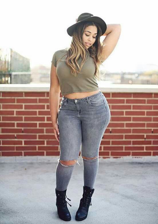 grey ripped jeans, an army green crop top, black boots, a hat for a comfy and sexy look