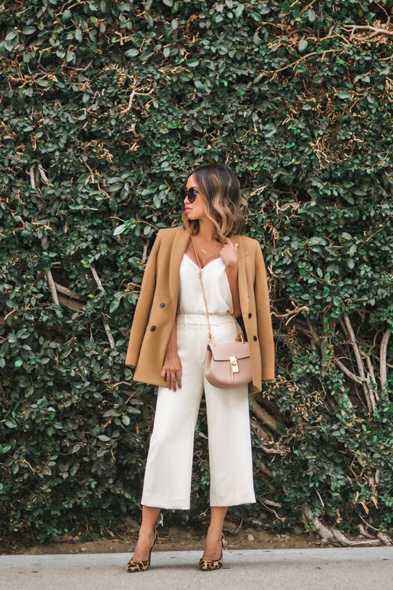 white culottes and a top, leopard shoes, a tan jacket and a blush bag