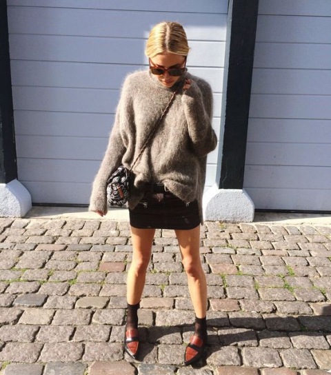With oversized sweater, mini skirt, flats and bag