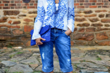 With printed blouse, beige lace up sandals and blue clutch