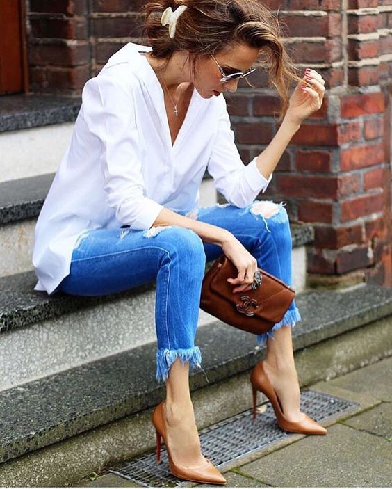 a white shirt, blue ripped and fringe skinnies, brown heels and a clutch for a casual look