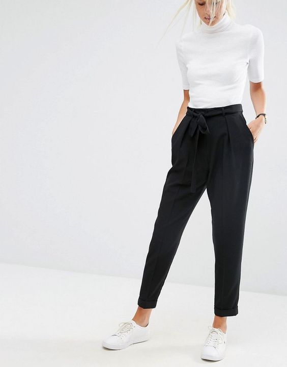 black pants with pockets and a draped top, a white top and sneakers for a business casual look