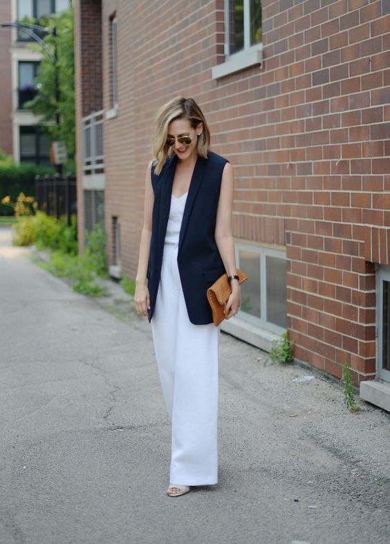 white wide pants, a white sleeveless top, a navy long vest, heeled sandals with a brown clutch