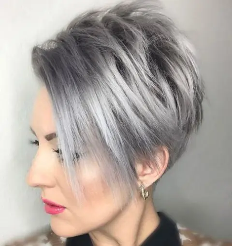 a pixie bob wiht long side bangs in trendy grey hair color looks chic