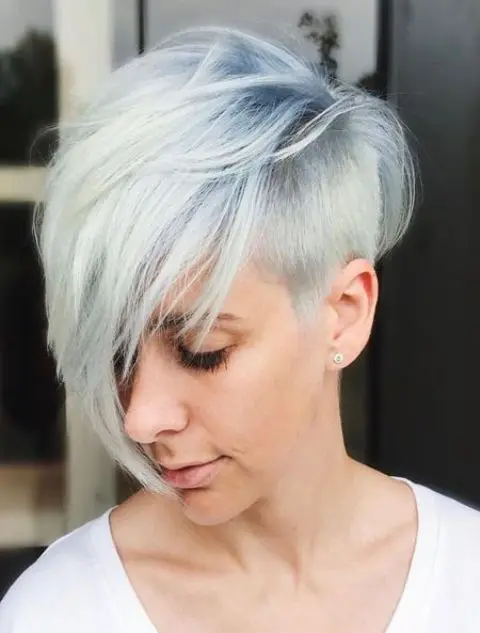 a longer pixie haircut with a side fringe and a chic blue to white balayage