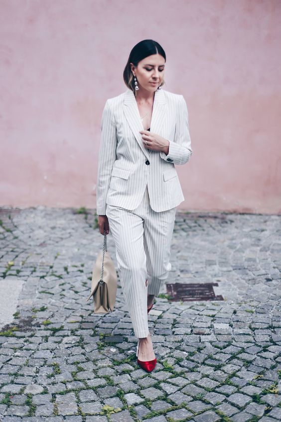 a white thin stripe pantsuit with a black top underneath, a neutral bag and red kitten heels