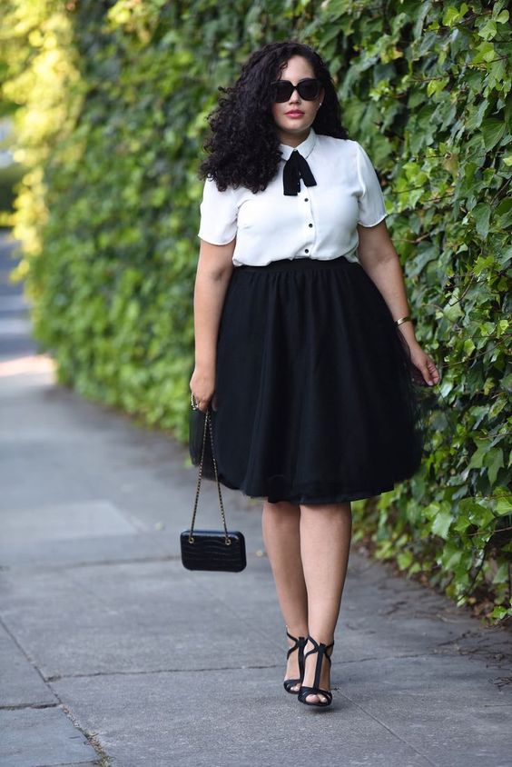 a black full skirt, a white blouse with black buttons and a bow and black shoes