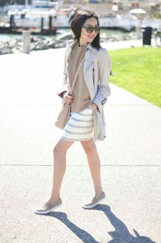 a tan top, a striped skirt, a grey trench, grey slipons and a tan bag for a girlish feel