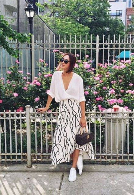 a white button down with cuffed sleeves, a printed midi skirt, whiet sneakers and a catchy bag