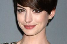 Anna Hathaway wearing a long dark brown pixie that emphasizes the beauty of the face farming it