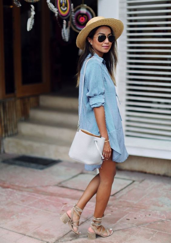 a chambray mini dress, a white bag, tan strappy heels and a hat comprise a cool relaxed look