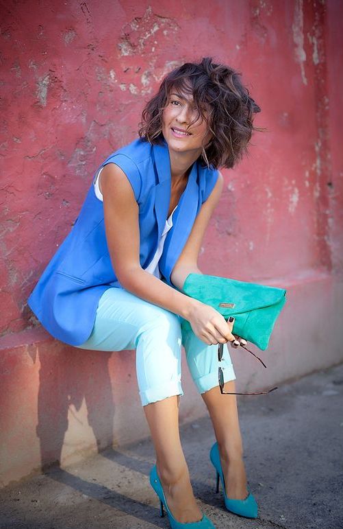 mint cropped pants, a white top, a bold blue vest, turquoise shoes and a clutch