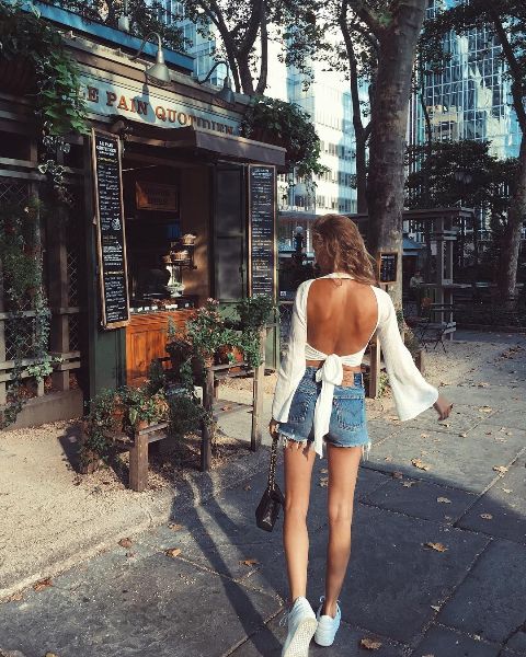 With denim shorts, white sneakers and black bag