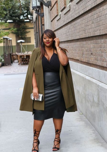 With olive green cape, black leather skirt, lace up sandals and clutch