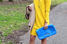 With yellow dress, blue clutch and beige coat