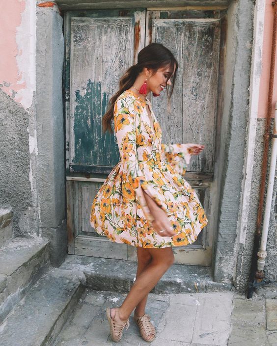 a cute mini dress with a yellow floral print, log sleeves, neutral lace up shoes and tassel earrings