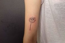 Black daisy tattoo on the arm