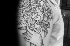 Hand holding flower and fern tattoo