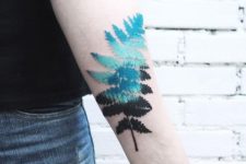 Turquoise and black fern tattoo on the arm