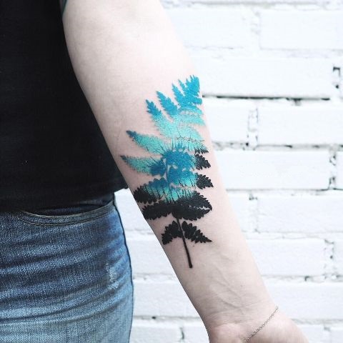 Turquoise and black fern tattoo on the arm