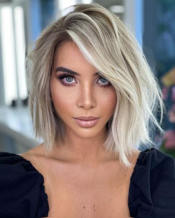 a lovely asymmetrical blonde bob with messy parting and a lot of volume plus waves is a cool and catchy idea to rock