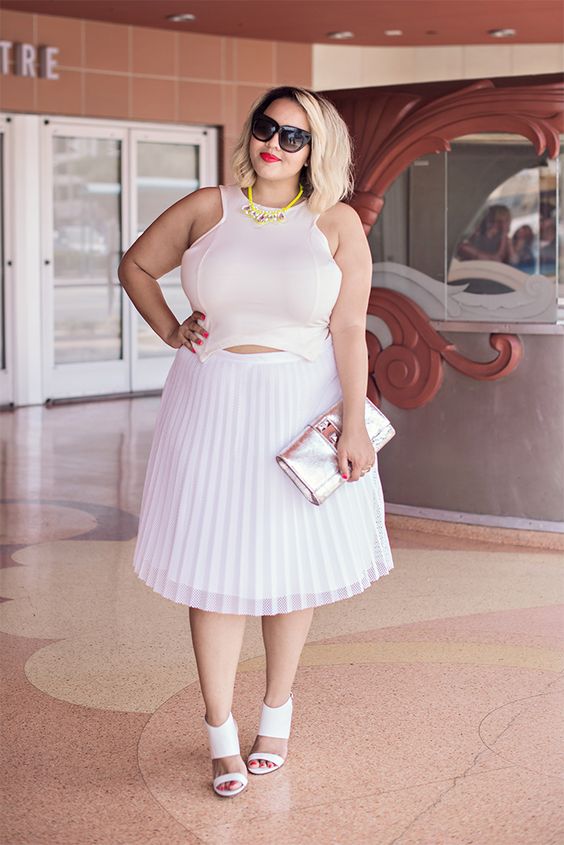 a pleated knee skirt, a crop top with no sleeves, a statement necklace, heeled sandals