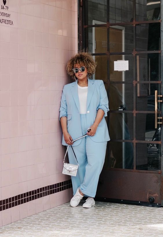 a powder blue suit, a white tee, white sneakers and a silver bag