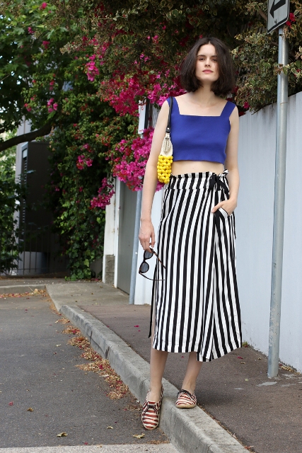 With blue crop top, striped shoes and yellow clutch