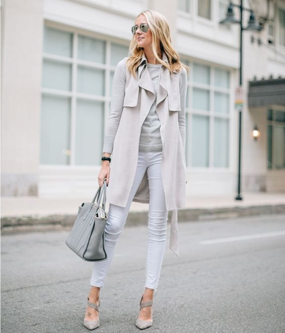 white jeans, a grey top, a neutral sleeveless coat, grey heels and a bag